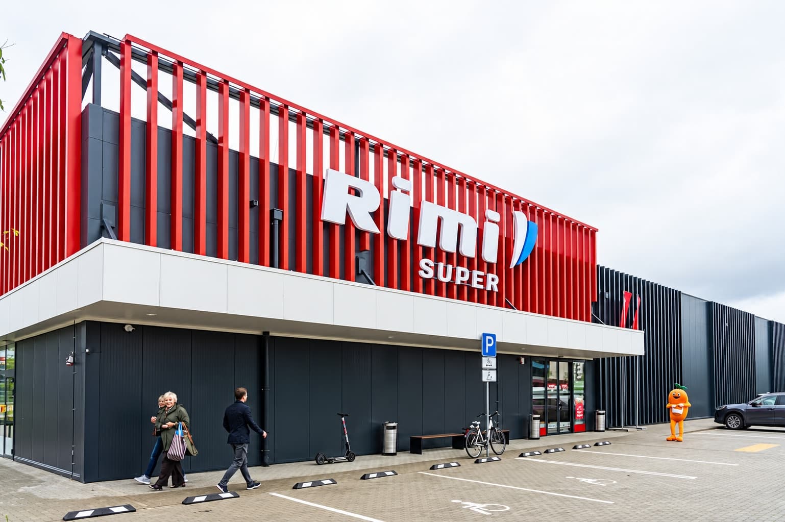 Rimi Super at Skanstes Street 17, Riga, with red vertical facade fins and customer parking in front.